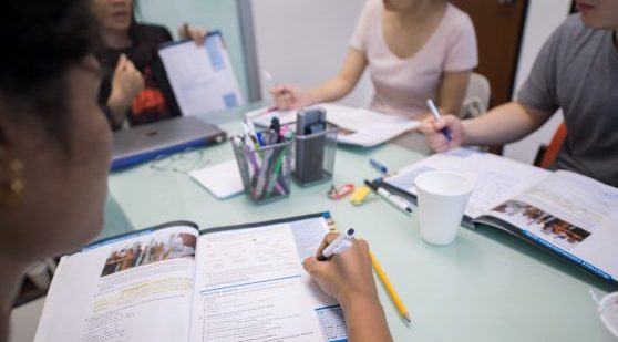 Small group of students doing English language exercises in books.